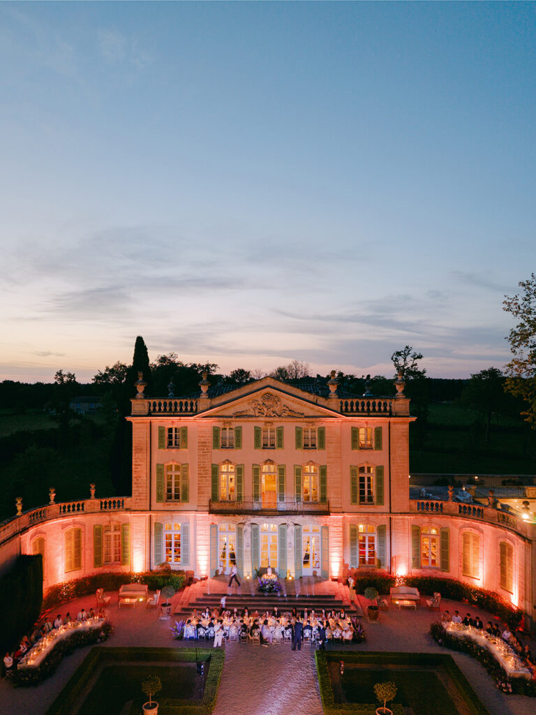 Aerial twilight view of the illuminated Château de Tourreau wedding dinner and floral courtyard design by Capucine Atelier Floral.