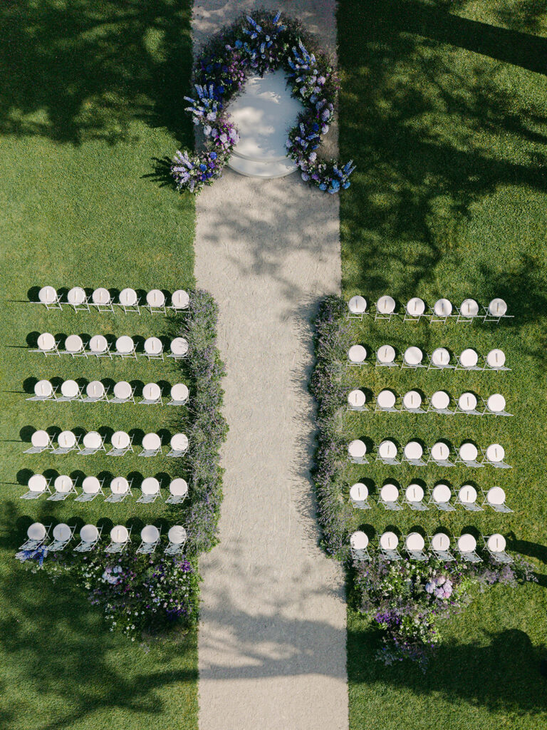 Aerial view of the symmetrical white seating, lavender aisle and floral stage created by Capucine Atelier Floral.