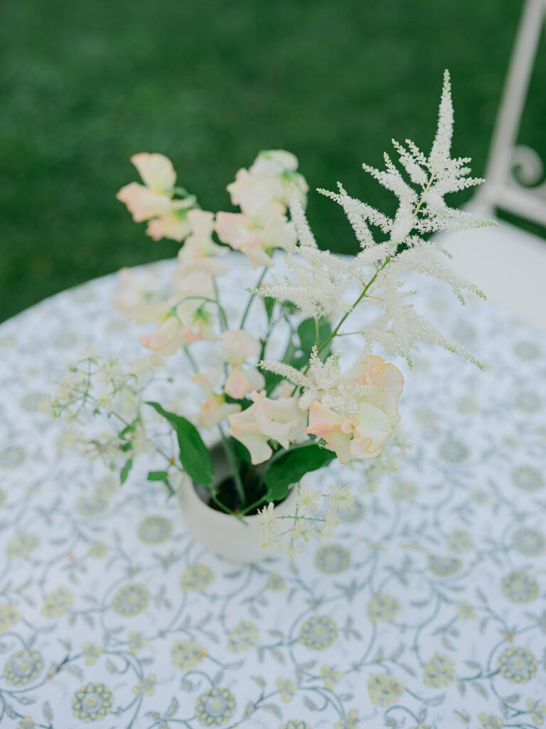 Airy white blossoms, pale peach flowers and green foliage create a delicate Provence cocktail centerpiece.