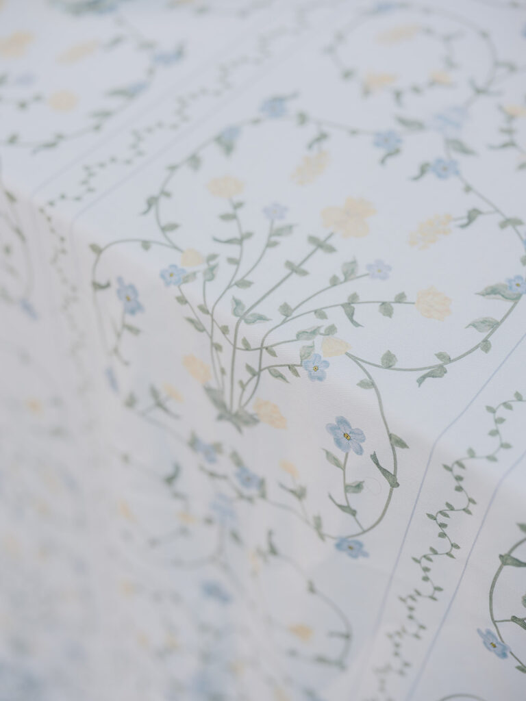 Close-up of the delicate blue and green botanical pattern printed across the wedding dinner tablecloth.