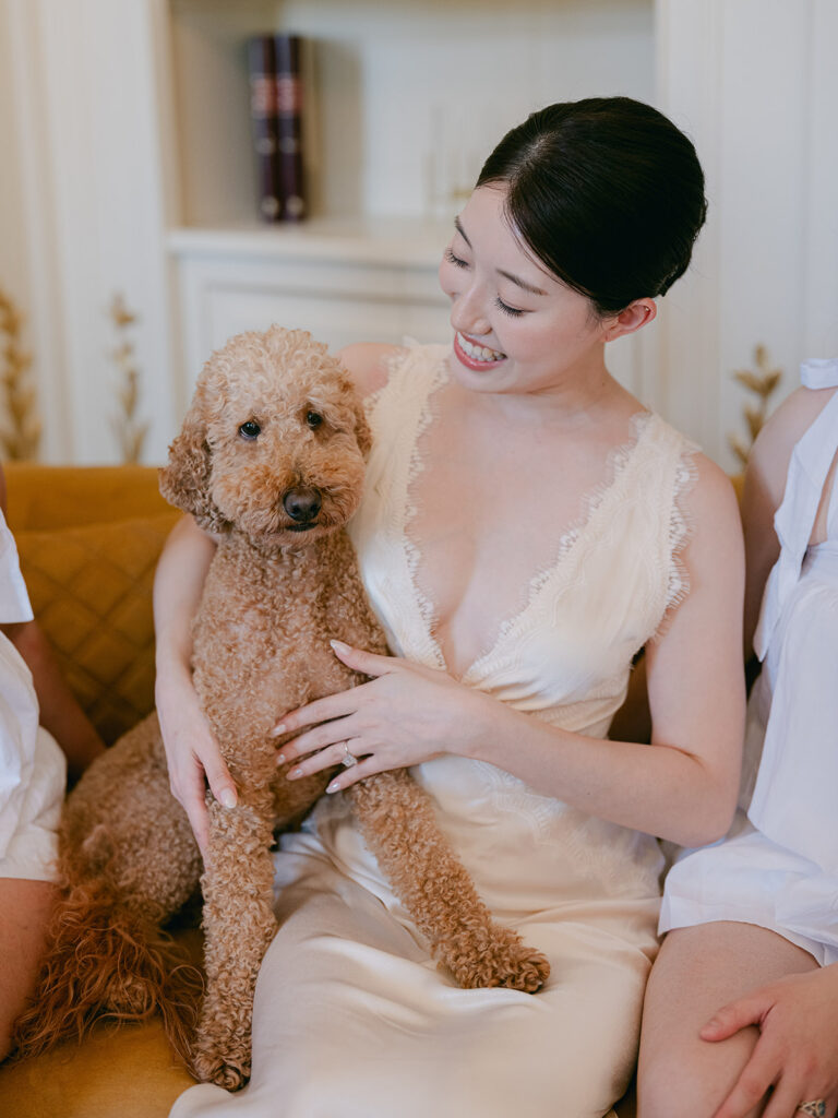 Casey smiles while holding her curly-haired dog during the bridal preparations at Château de Tourreau.