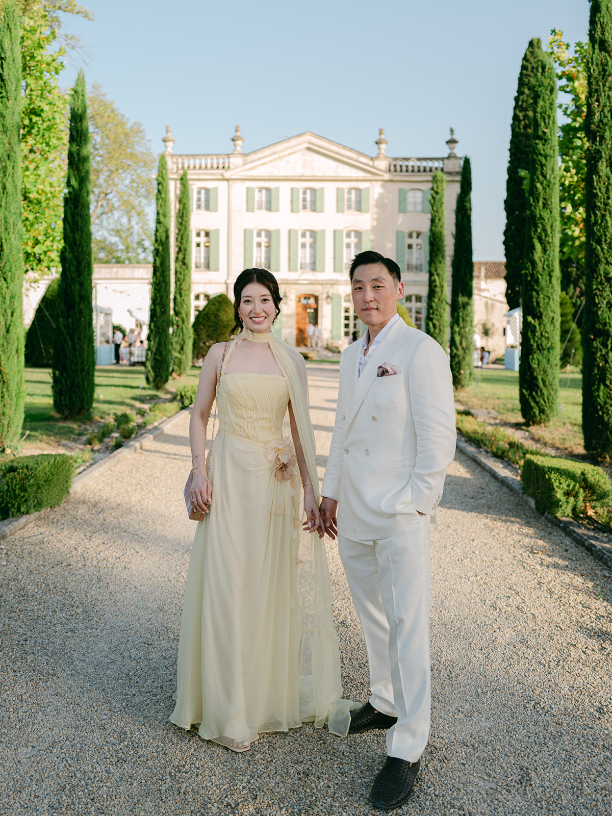 Casey and James posing together on the garden path with the sunlit façade of Château de Tourreau behind them.