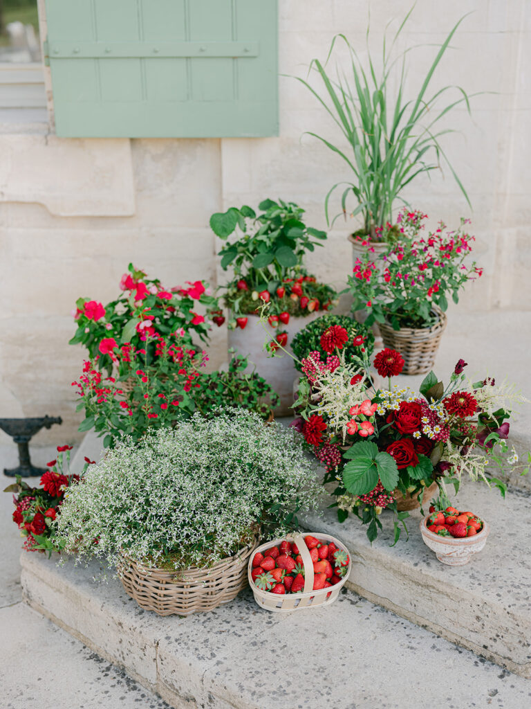 Garden-style staircase installation combining red flowers, strawberry plants, baskets of fruit and sculptural greenery.