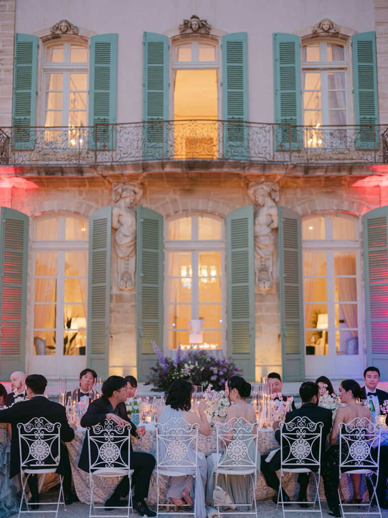 Evening wedding dinner illuminated against Château de Tourreau with floral tables and candlelight by Capucine Ate