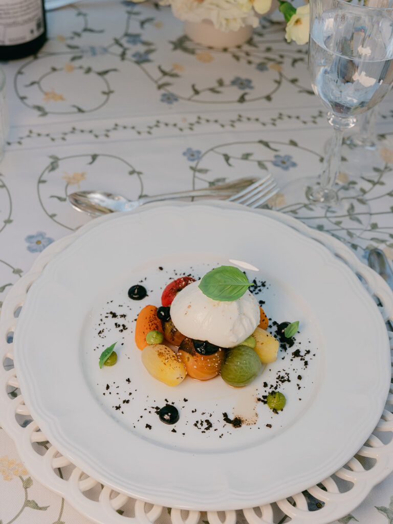 Artfully plated wedding dinner starter served on white china over the botanical-patterned tablecloth.