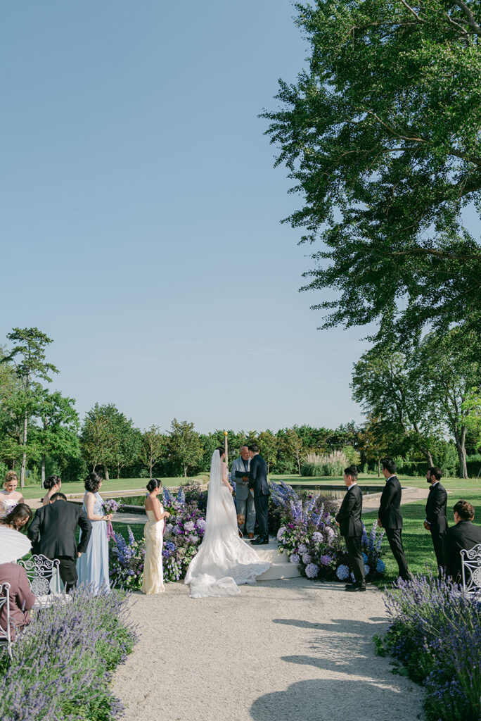 Outdoor Château de Tourreau ceremony framed by lavender and purple garden flowers.
