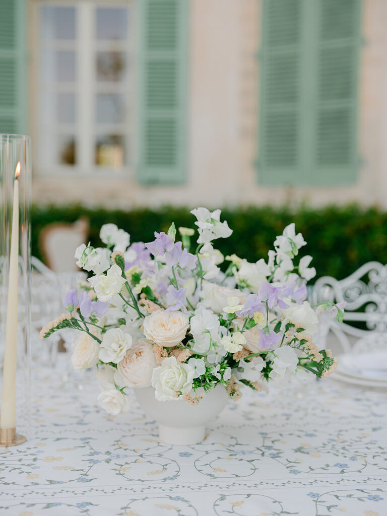 Peach garden roses, white flowers and pale lilac blooms form a romantic low centerpiece for the Provence dinner.