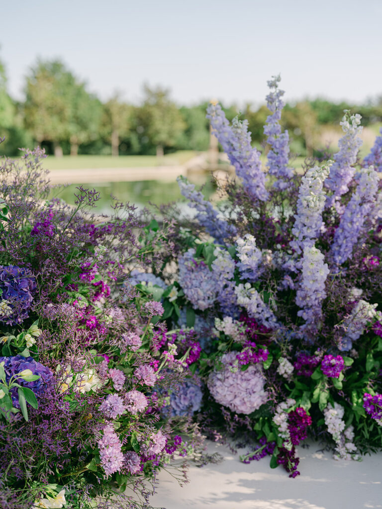 Abundant purple and lavender flowers frame the reflecting pool in an installation by Capucine Atelier Floral.