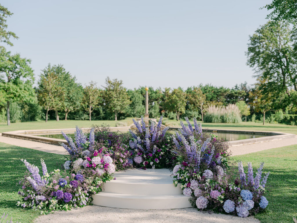 Wide view of the flower-filled ceremony platform positioned before the reflecting pool in the Provence garden.