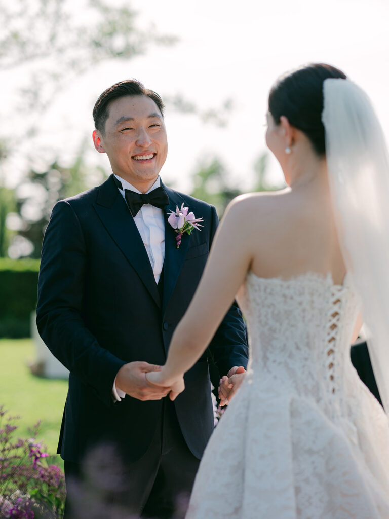 James smiles at Casey while holding her hands during their wedding vows at Château de Tourreau.