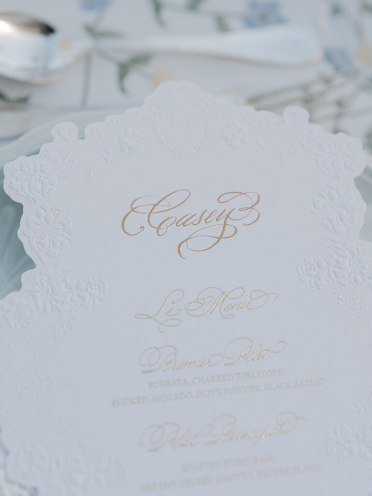 Embossed ivory wedding menu printed in elegant gold calligraphy for Casey and James’s outdoor dinner.