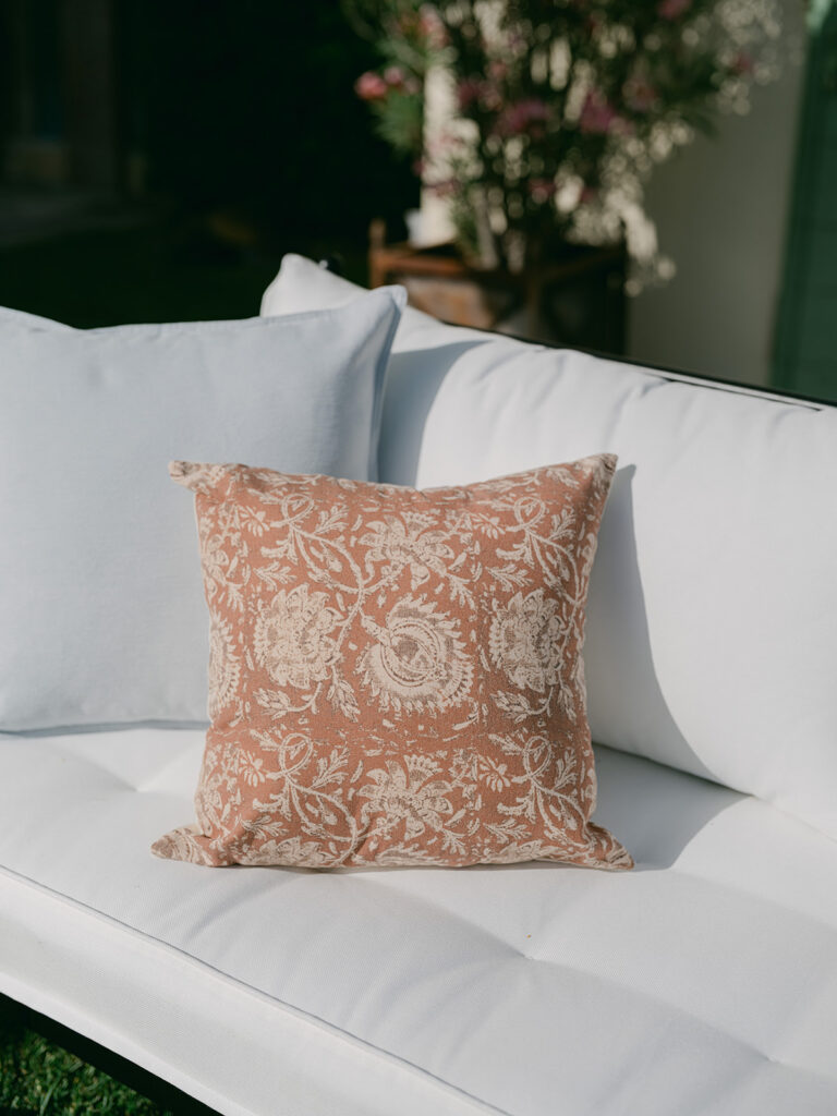 Terracotta patterned cushion styled on a white outdoor sofa in the elegant wedding cocktail lounge.