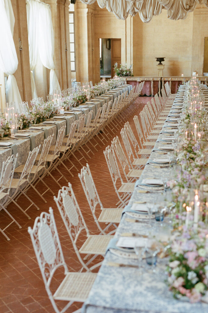 Elegant banquet tables with blue patterned linens and pastel flowers fill the reception hall at Château de Vallery.