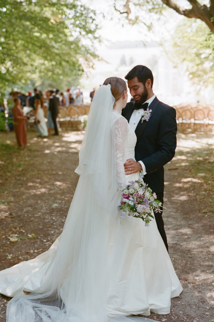 Kaylin and Paul face each other beneath the trees after their garden ceremony at Château de Vallery.