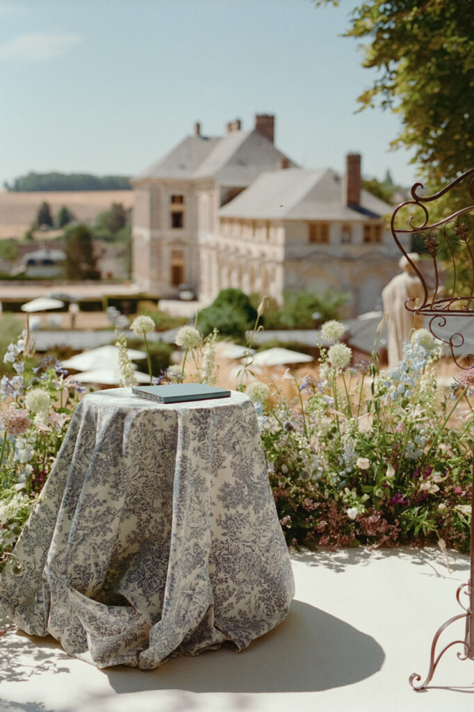 Ceremony signing table framed by pastel garden flowers with Château de Vallery in the background.