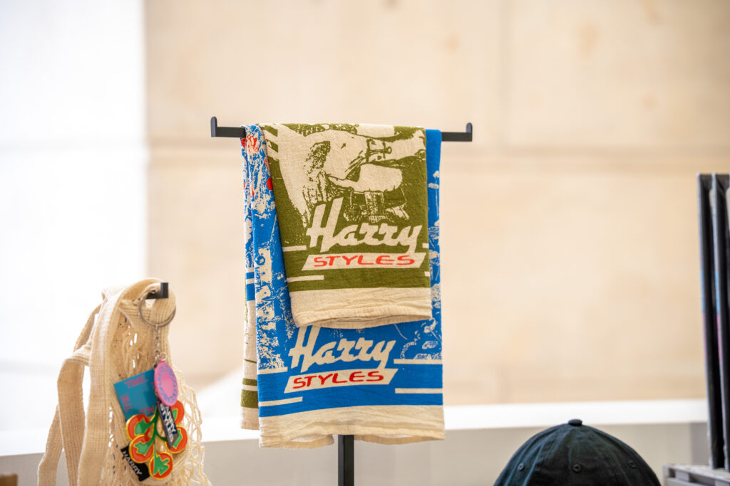 Blue and green Harry Styles tea towels displayed as limited-edition merchandise in the Paris pop-up.