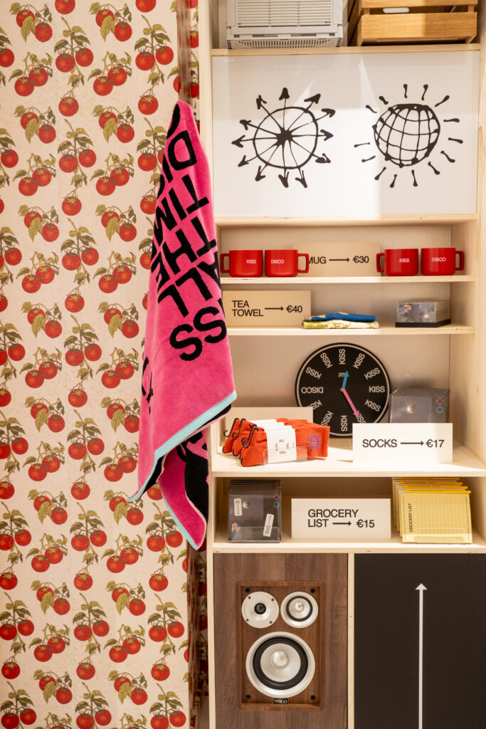 Kiss Disco towel, mugs, socks, vinyl and accessories arranged on shelves at the Paris album pop-up.