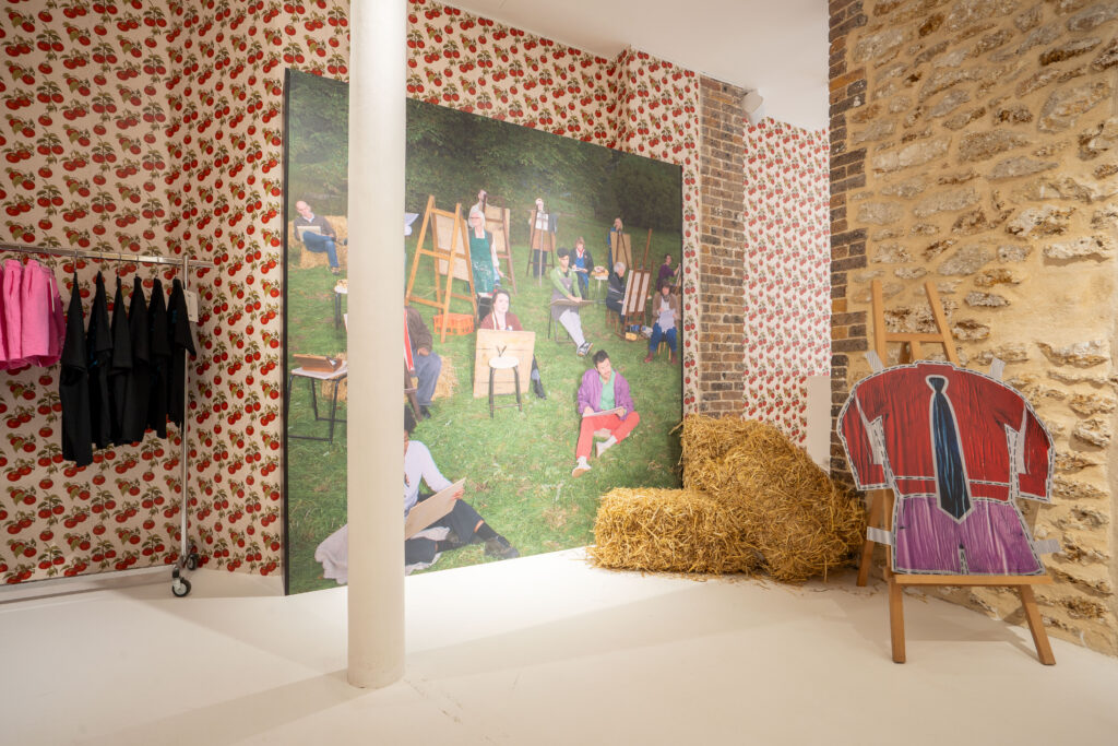 Art-class scene with easels, hay bales and a cut-out outfit inside the Harry Styles Paris pop-up.
