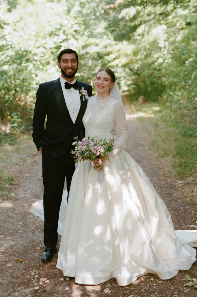 Kaylin and Paul pose as newlyweds beneath the trees in the gardens of Château de Vallery.