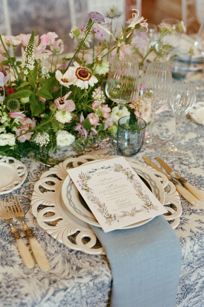 Garden-style centerpiece of pink, lilac and white flowers on a blue toile wedding table at Château de Vallery.