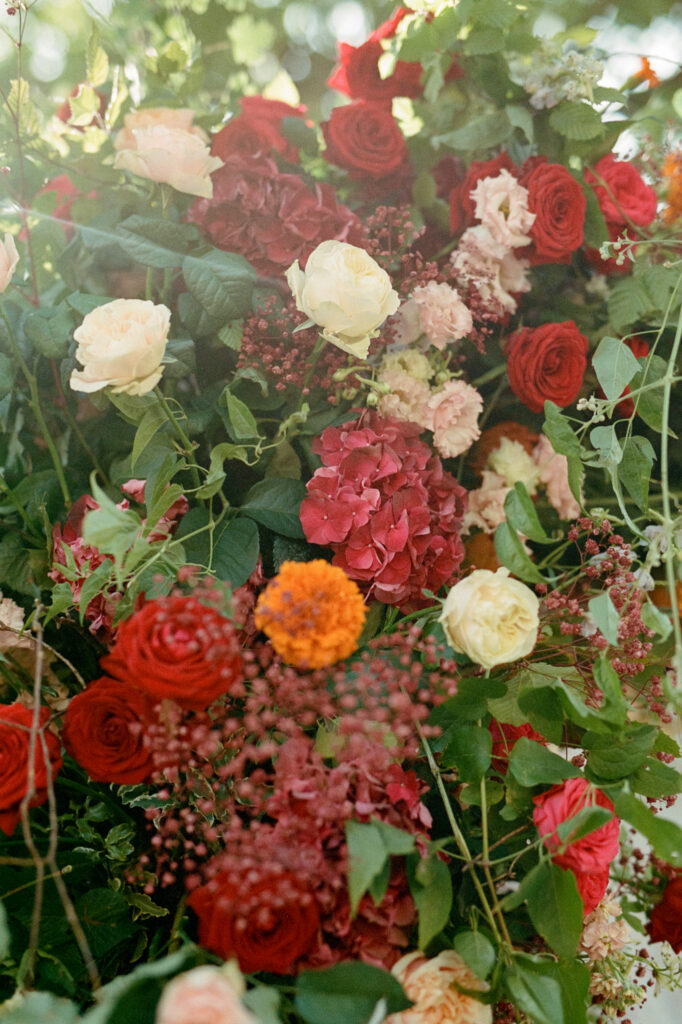 Rich red, burgundy, blush and orange ceremony flowers by Capucine Atelier Floral for Kaylin and Paul’s Indian wedding.